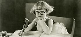 vintage photo of a young child holding a quill pen and frowning